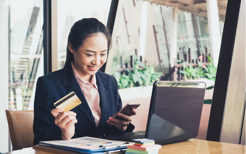 EQB, Owner of EQ Bank, to Acquire PC Financial - Woman with card and phone at desk with computer