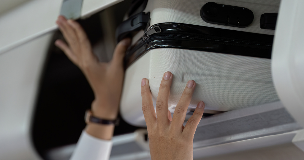 Guide des dimensions de bagages chez WestJet - Dimensions des bagages de WestJet – image en vedette – mains plaçant une valise dans le compartiment supérieur